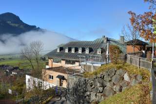 Jugendbildungstätte Hindelang in der Morgensonne, im Hintergrund Nebelschwaden.